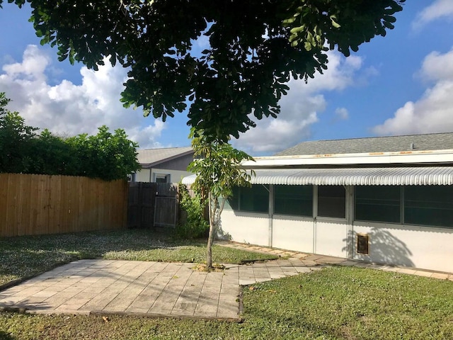 back of property with a yard, fence, stucco siding, and a patio