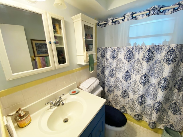 bathroom with toilet, vanity, a shower with curtain, and tile walls