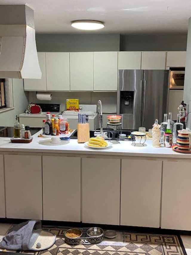 kitchen with white cabinetry, stainless steel refrigerator with ice dispenser, and exhaust hood