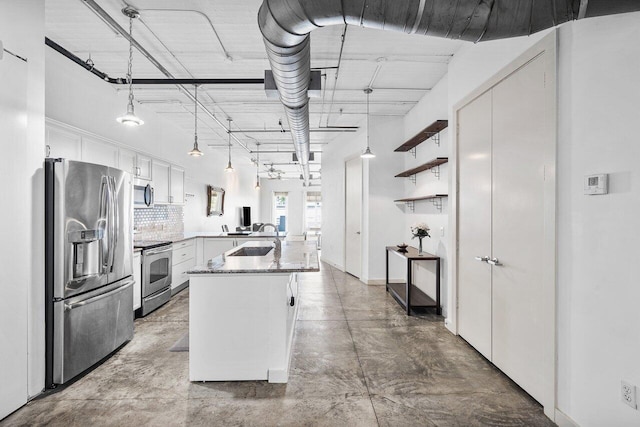 kitchen featuring stainless steel appliances, white cabinetry, sink, an island with sink, and dark stone counters