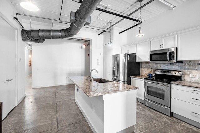 kitchen featuring white cabinetry, sink, light stone countertops, appliances with stainless steel finishes, and a center island with sink