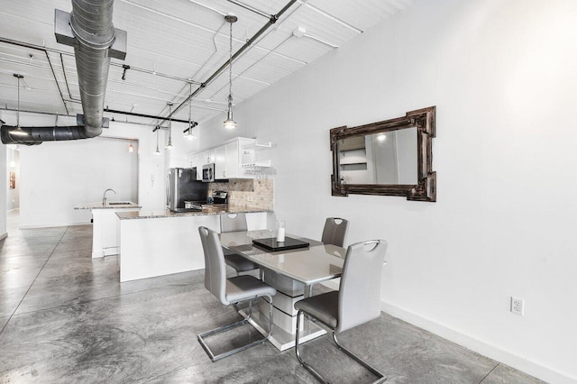 dining space featuring a high ceiling, concrete floors, and sink