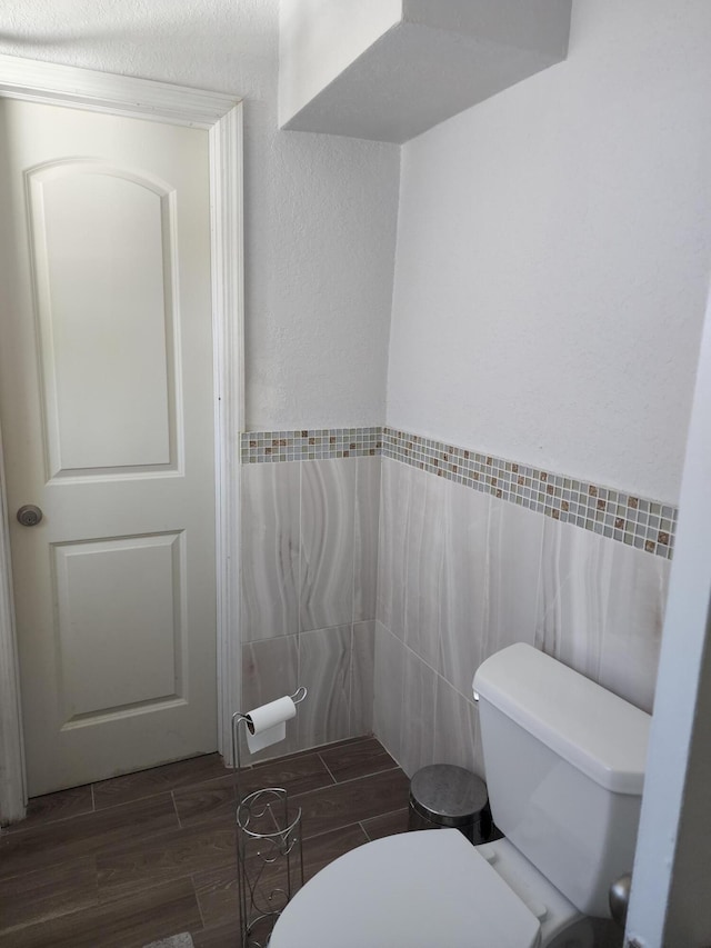 bathroom with tile walls, hardwood / wood-style floors, and toilet