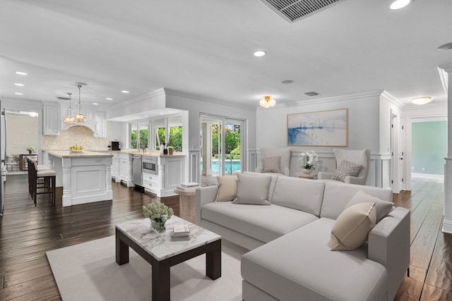 living room with an inviting chandelier, crown molding, and dark wood-type flooring