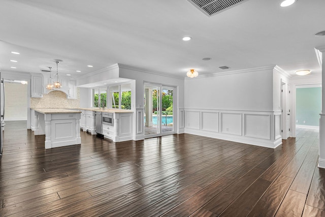 unfurnished living room with crown molding, an inviting chandelier, and dark hardwood / wood-style flooring