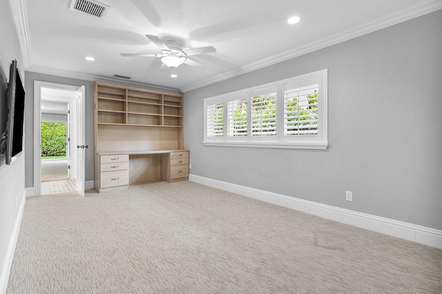 unfurnished bedroom with ceiling fan, light carpet, built in desk, and crown molding