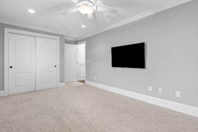 unfurnished bedroom featuring a closet, crown molding, carpet, and ceiling fan