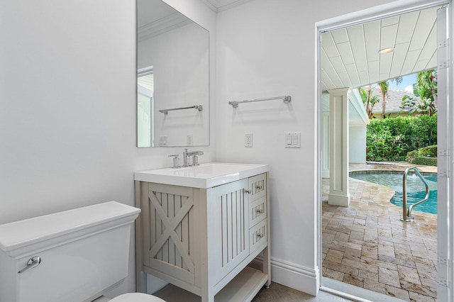 bathroom with ornamental molding, vanity, and toilet