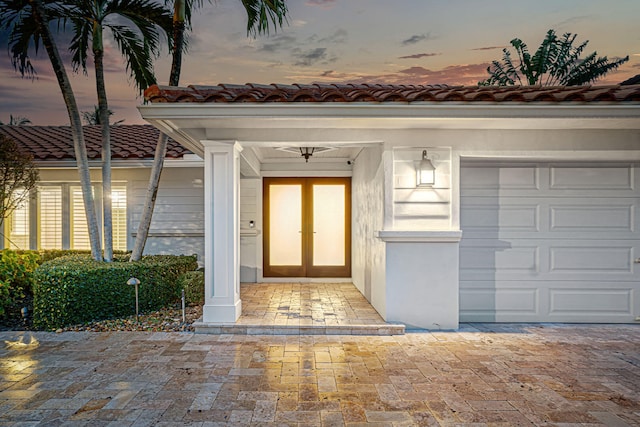 exterior entry at dusk with french doors and a garage