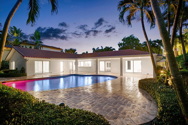 pool at dusk featuring a patio