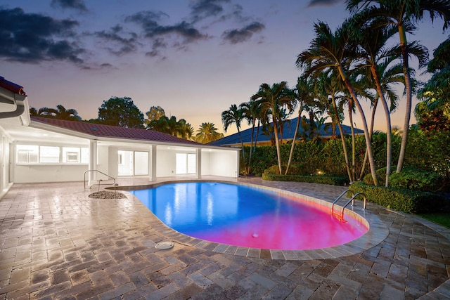 pool at dusk with a patio