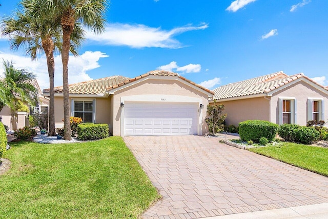 view of front of house with an attached garage, a front lawn, decorative driveway, and stucco siding