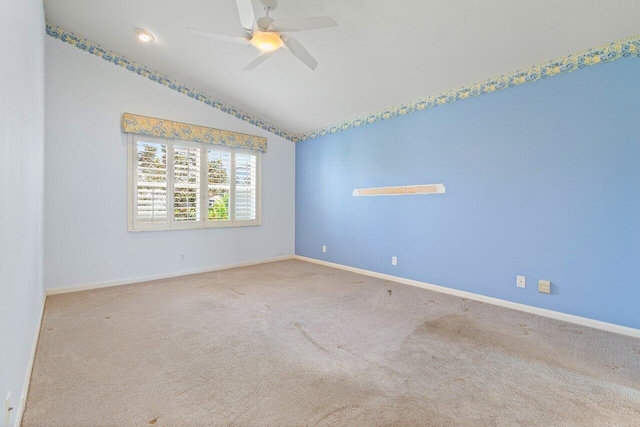 empty room featuring ceiling fan, vaulted ceiling, and carpet floors