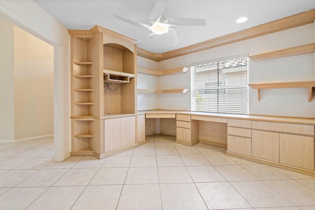 unfurnished office featuring ceiling fan, built in desk, ornamental molding, and light tile patterned floors