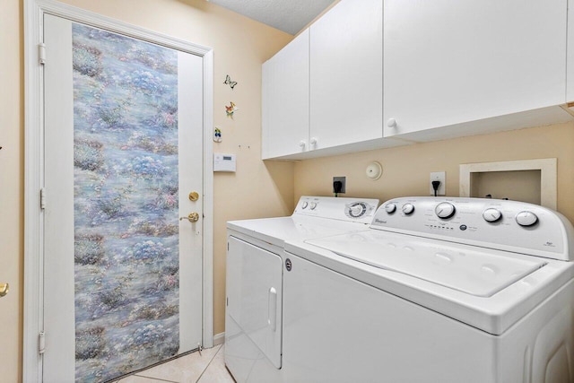 clothes washing area with independent washer and dryer, a textured ceiling, light tile patterned floors, and cabinets