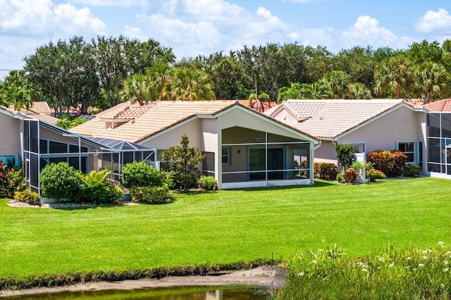 rear view of property featuring a sunroom and a lawn