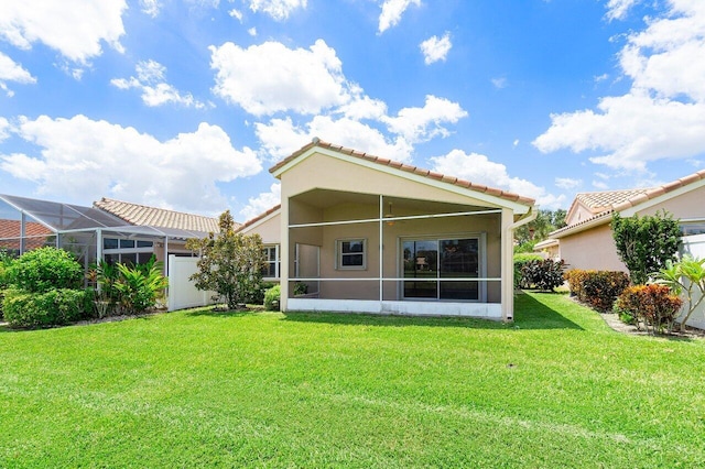 rear view of property with a lawn and glass enclosure