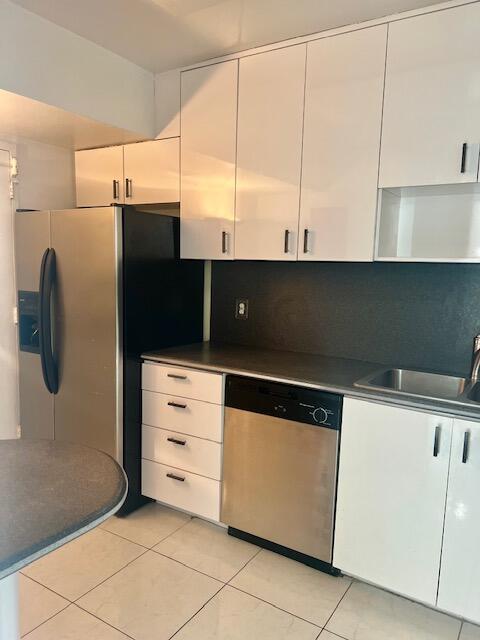 kitchen featuring light tile patterned flooring, white cabinets, stainless steel appliances, and backsplash