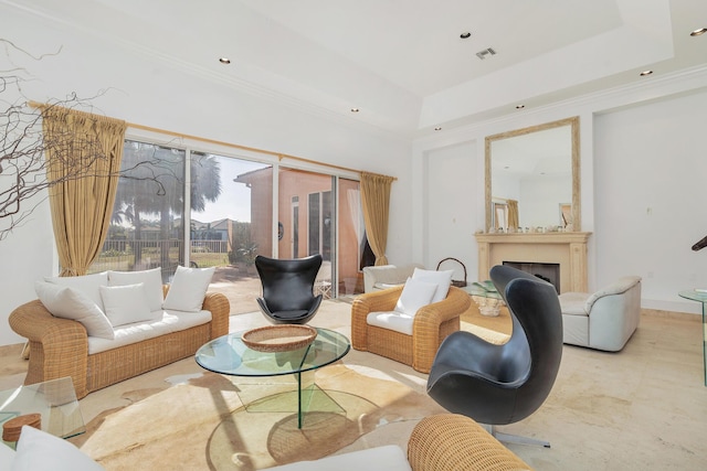 living room with ornamental molding, a tray ceiling, a fireplace, and visible vents