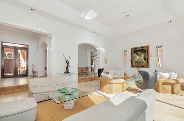 living area featuring arched walkways, a tray ceiling, decorative columns, recessed lighting, and ornamental molding