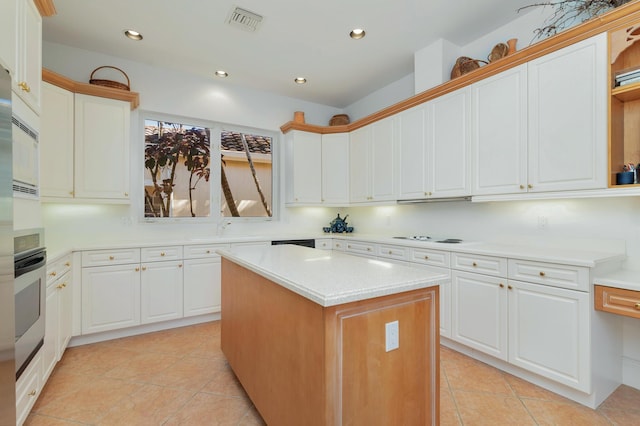 kitchen featuring white cabinets, stainless steel oven, a kitchen island, and light tile patterned flooring