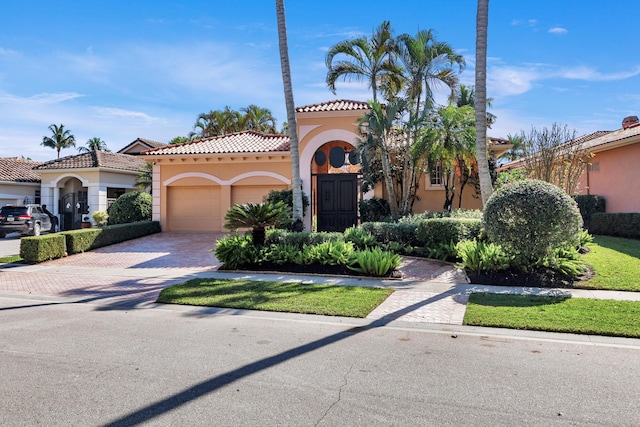 mediterranean / spanish-style house featuring decorative driveway, a tiled roof, an attached garage, and stucco siding