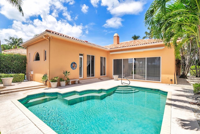 back of house featuring an outdoor pool, a chimney, a patio area, and stucco siding