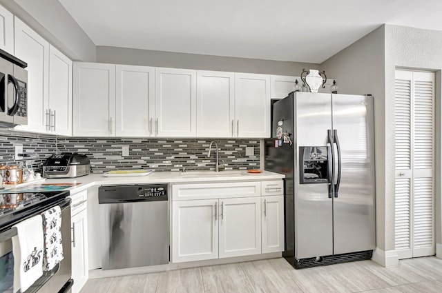 kitchen with white cabinets, stainless steel appliances, decorative backsplash, and sink