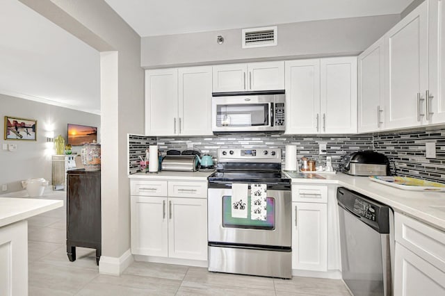 kitchen with ornamental molding, white cabinetry, backsplash, stainless steel appliances, and light tile patterned flooring