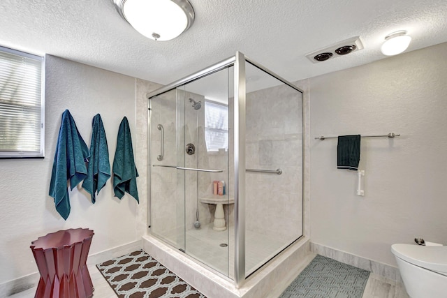 bathroom with a textured ceiling, toilet, and an enclosed shower