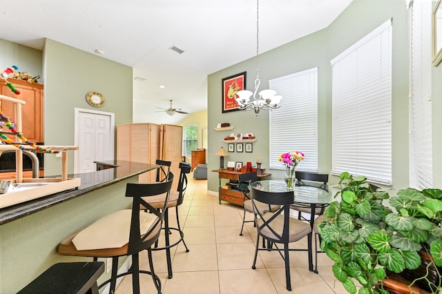 dining space featuring ceiling fan with notable chandelier, lofted ceiling, and light tile patterned floors