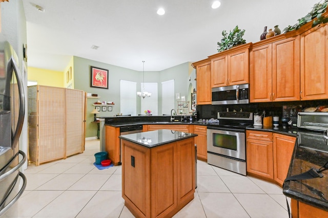 kitchen with appliances with stainless steel finishes, decorative light fixtures, sink, kitchen peninsula, and a center island