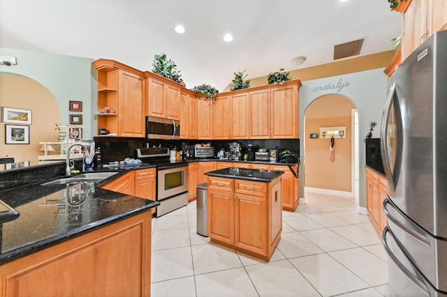 kitchen featuring appliances with stainless steel finishes, light tile patterned floors, decorative backsplash, sink, and kitchen peninsula