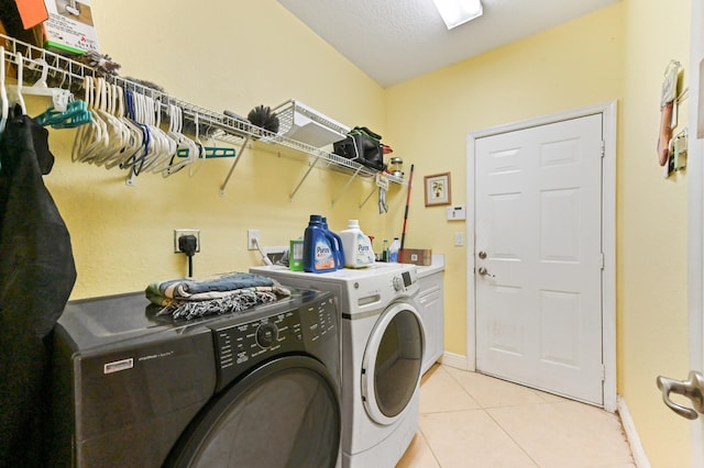 laundry room featuring washing machine and dryer, a textured ceiling, and light tile patterned flooring