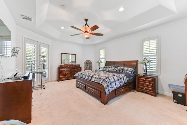 carpeted bedroom featuring ceiling fan and a tray ceiling