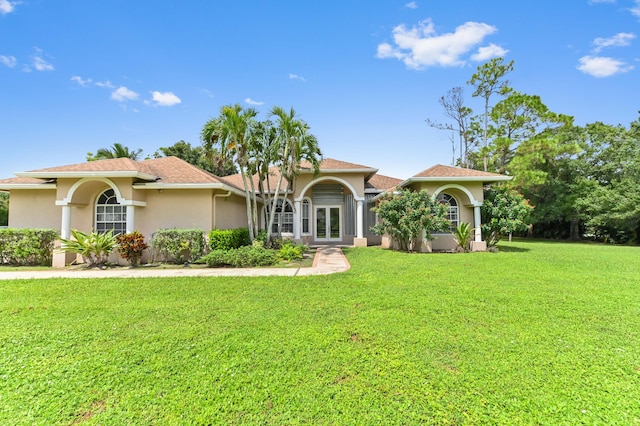 mediterranean / spanish-style home featuring a front lawn and french doors