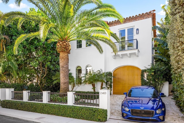 mediterranean / spanish-style home featuring a fenced front yard, stucco siding, a tile roof, and a balcony