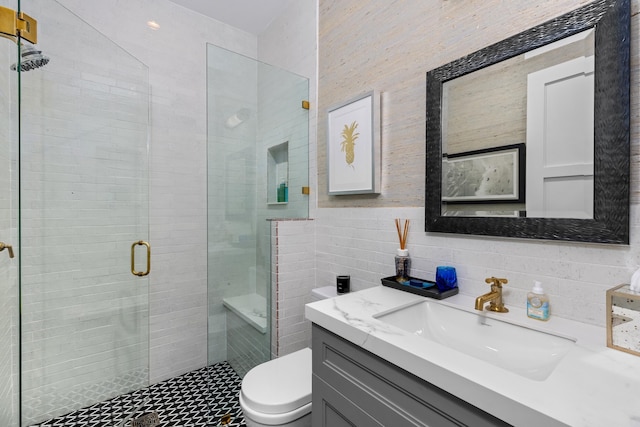 bathroom featuring vanity, toilet, a shower with door, and tile walls