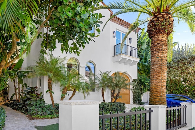 view of front of home with a fenced front yard, stucco siding, a tiled roof, and a balcony