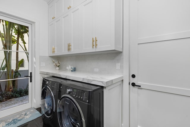 clothes washing area with washing machine and clothes dryer and cabinets