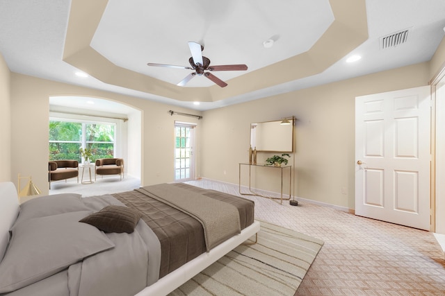 bedroom with a raised ceiling, light carpet, and ceiling fan