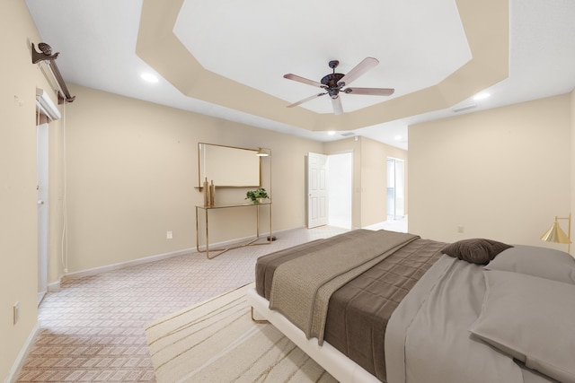 carpeted bedroom featuring ceiling fan and a raised ceiling