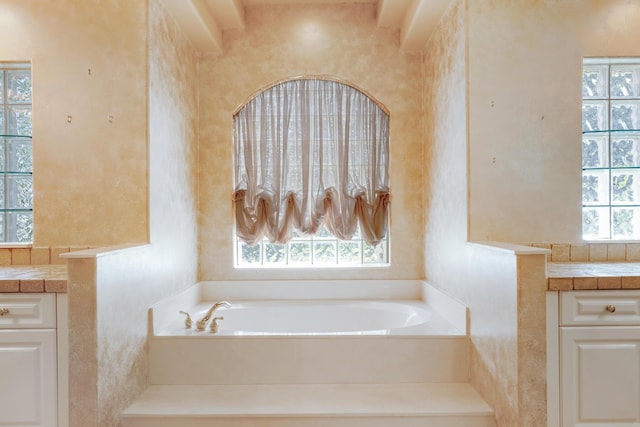 bathroom featuring a bathing tub, vanity, and a healthy amount of sunlight