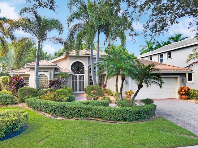 mediterranean / spanish home with a garage and a front lawn