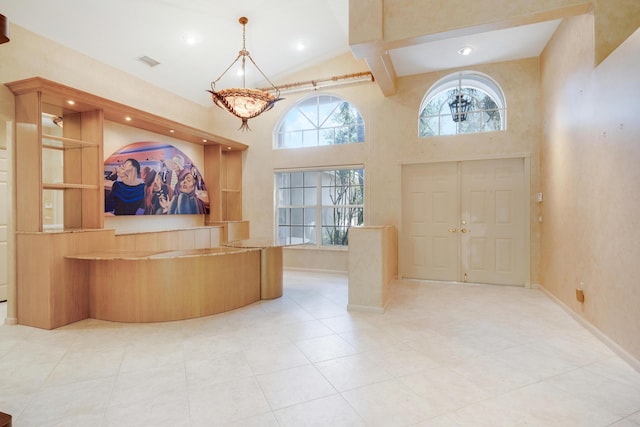 tiled entrance foyer featuring beam ceiling and a towering ceiling