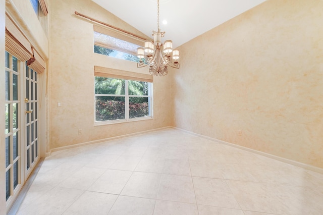 tiled spare room with high vaulted ceiling and a chandelier