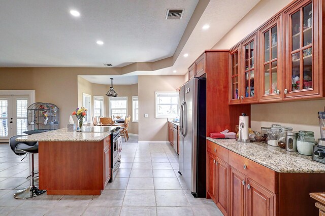 kitchen with appliances with stainless steel finishes, a healthy amount of sunlight, light tile patterned floors, and light stone countertops