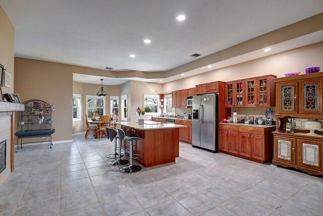 kitchen with stainless steel appliances, light tile patterned floors, a kitchen breakfast bar, a center island, and hanging light fixtures