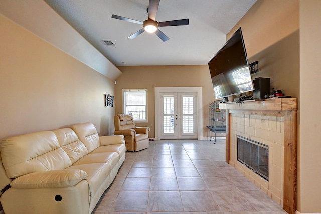 living room with ceiling fan, light tile patterned flooring, french doors, and a tiled fireplace