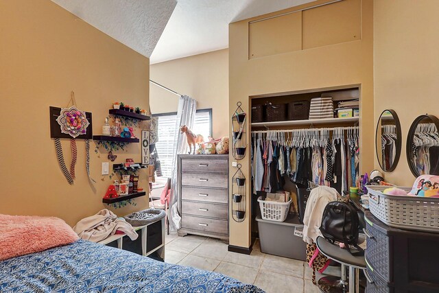 bedroom with a closet, vaulted ceiling, and light tile patterned floors